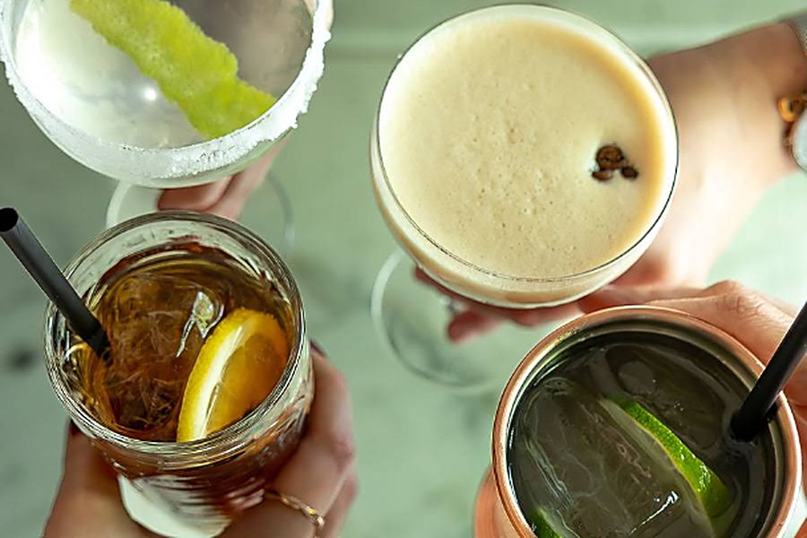 Quatro cocktails a brindar sobre uma mesa de mármore no Velvet, em Pedras Rubras